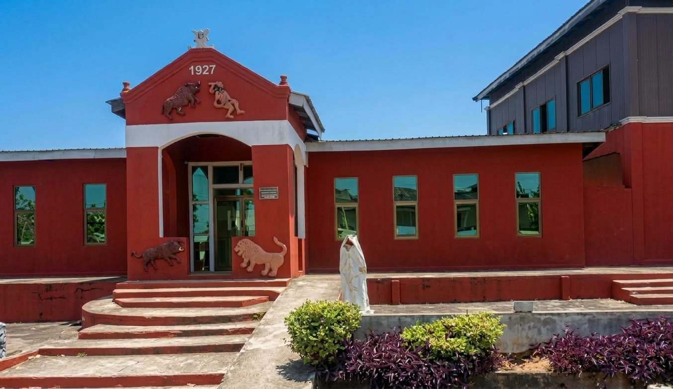 The Royal Palace of Esiama — red forecourt with Adinkra emblems, 1927 gable
